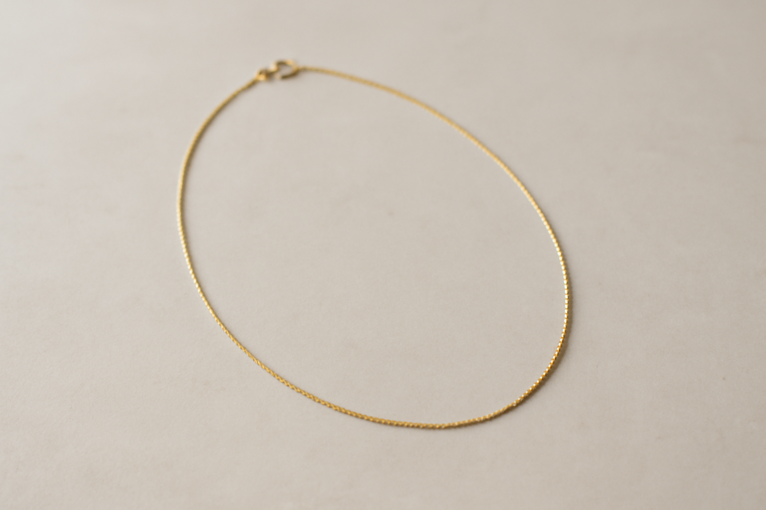 collier fin pose sur table minimaliste